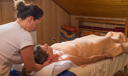 Une masseuse soutient la tête et la nuque d'une femme allongée sur le dos