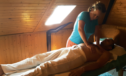 Une masseuse appuie des deux mains sur le torse d'un homme allongé sur le dos, sous une fenêtre de toit